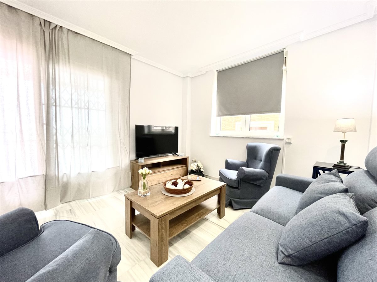 Salón con sofá, cojines y televisión para relajarse